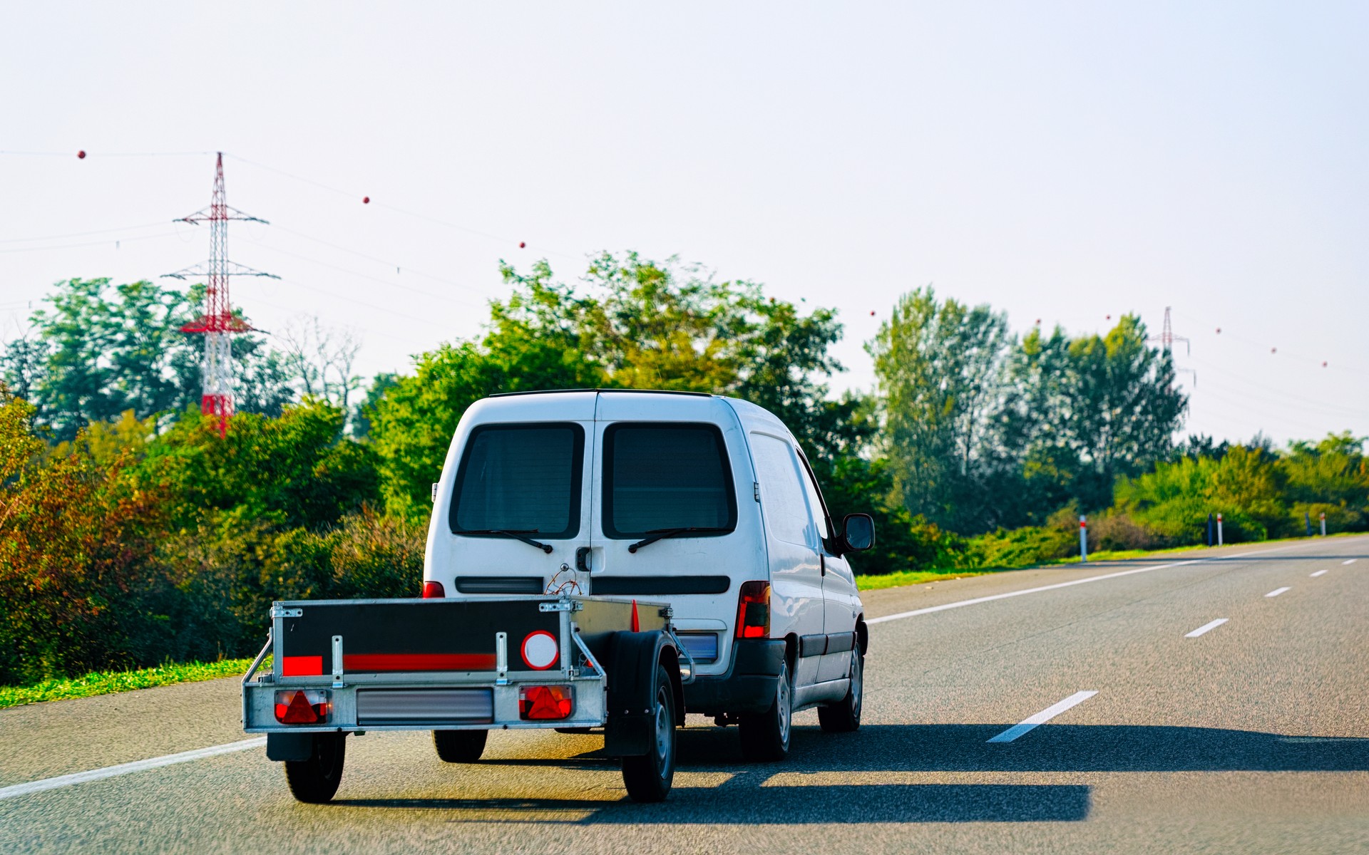 Mini van carrying trailer in asphalt road in Slovenia