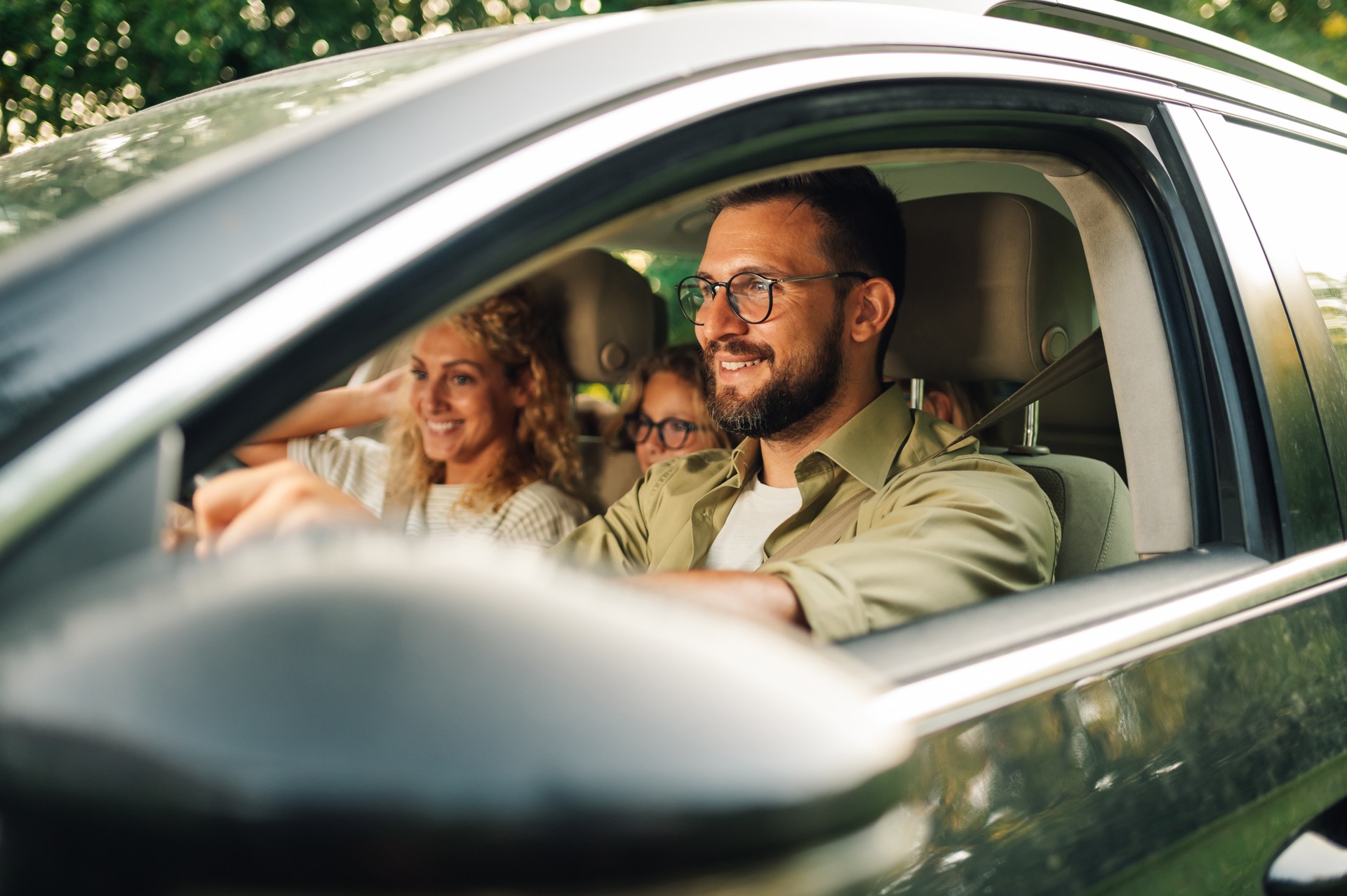 Portrait of a father driving a new car while riding with his family